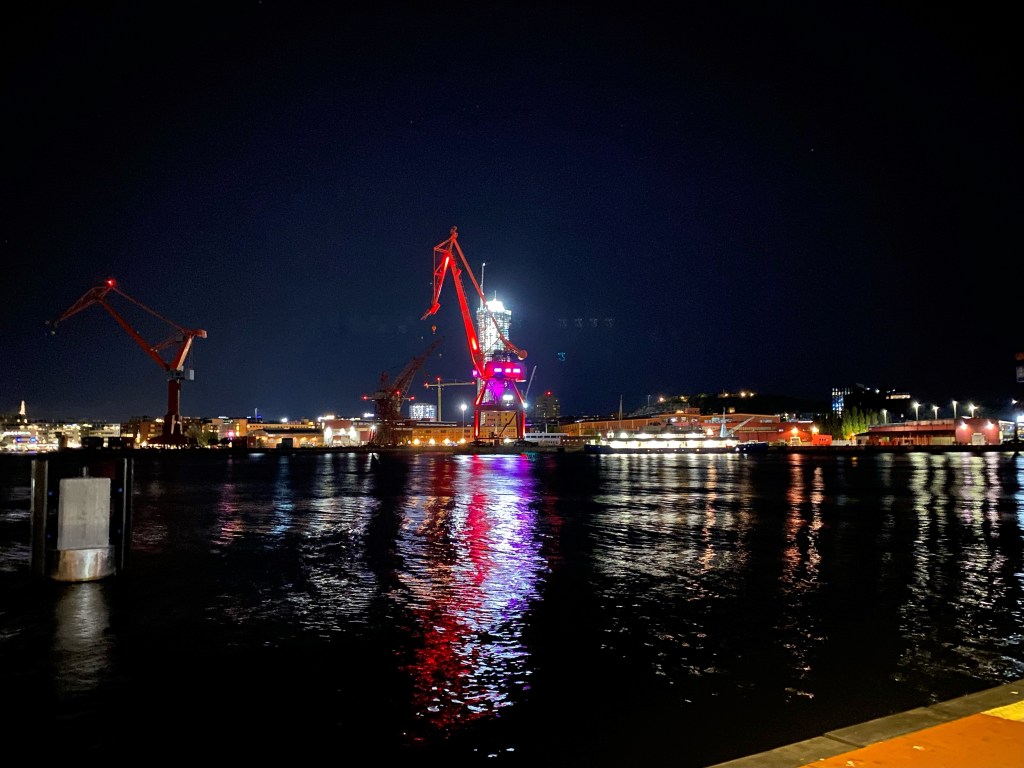 Night picture of a harbour crane lit in red and purple